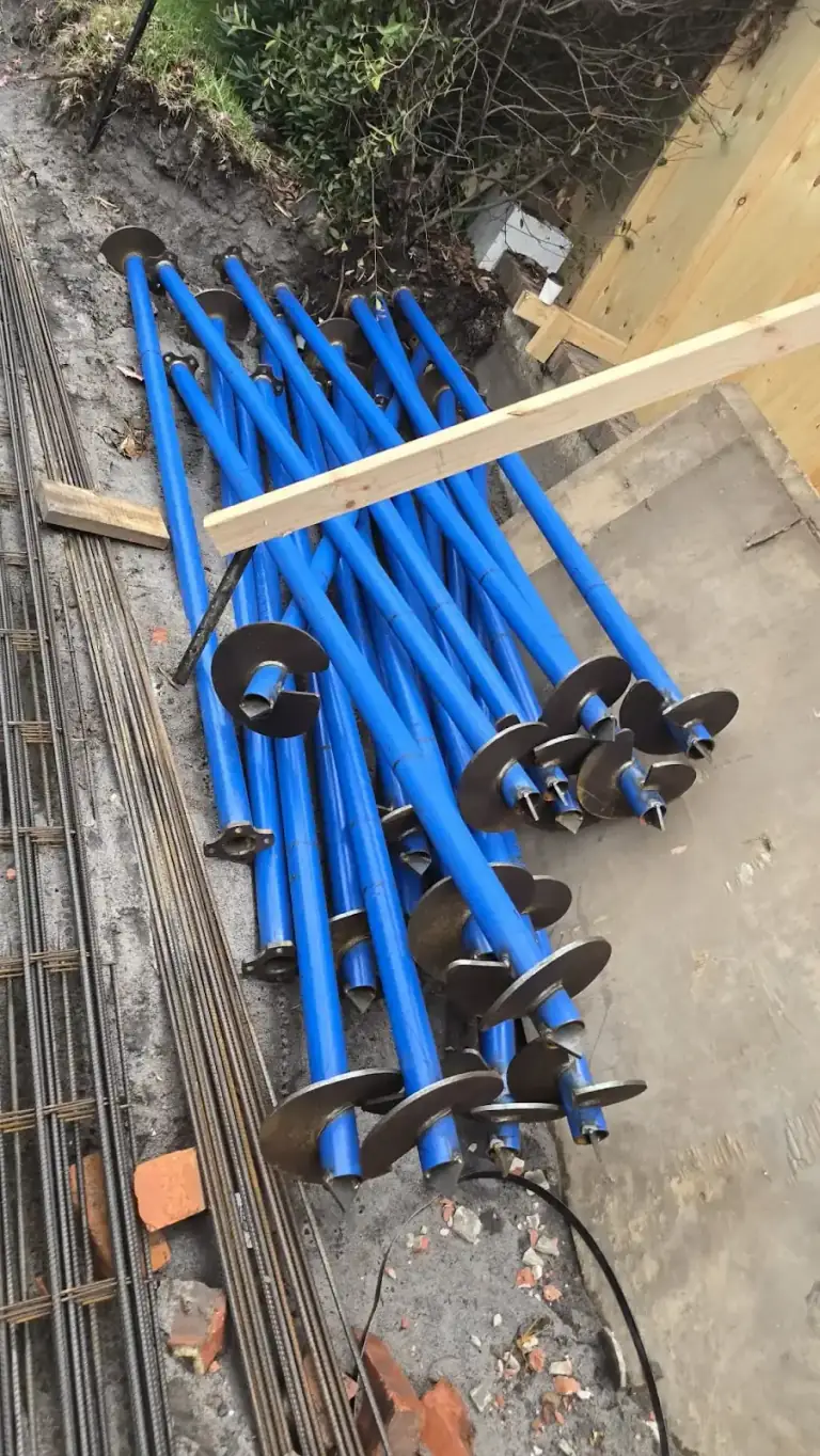 Screw piles and reinforcement prepared beside an excavated building area
